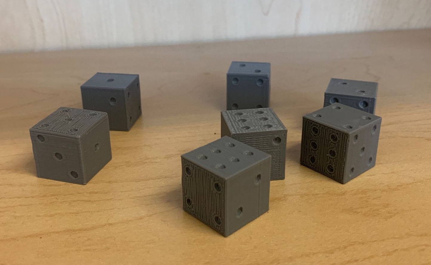 <strong>Figure 2.</strong> Seven weighted six-sided dice that were fabricated with a 3D printer. Figure courtesy of Jake Price.