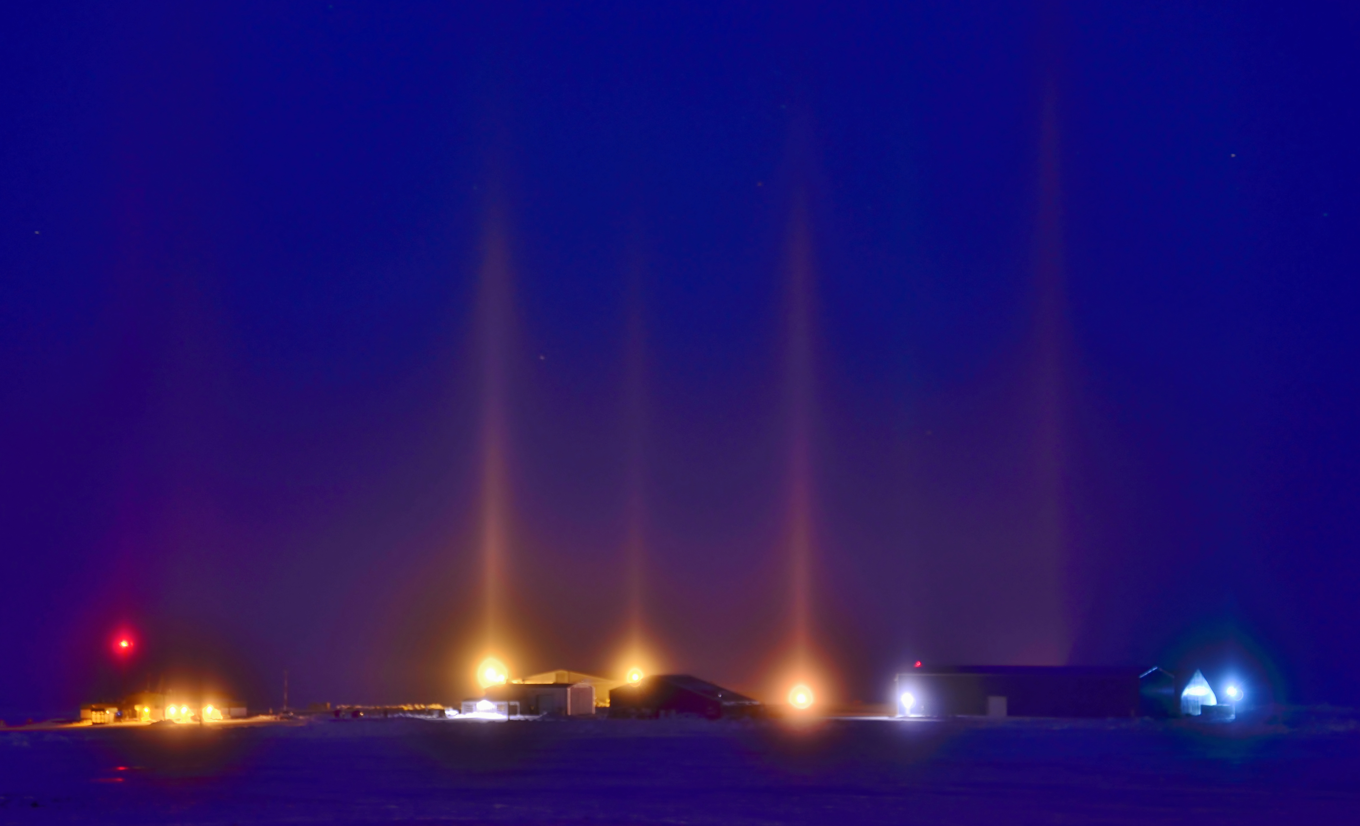 <strong>Figure 1.</strong> Light pillars—including these examples over Cambridge Bay in Nunavut, Canada—form when light shines through atmospheric ice crystals. The crystals align as they fall through turbulent air, which allows for coherent light scattering. Figure courtesy of <a href="https://www.flickr.com/photos/37967119@N08/17239657746/" rel="noopener noreferrer" target="_blank">Eric Van Lochem and Flickr</a> under the <a href="https://creativecommons.org/licenses/by-sa/2.0/" rel="noopener noreferrer" target="_blank">Attribution-ShareAlike (CC BY-SA 2.0) Generic license</a>.