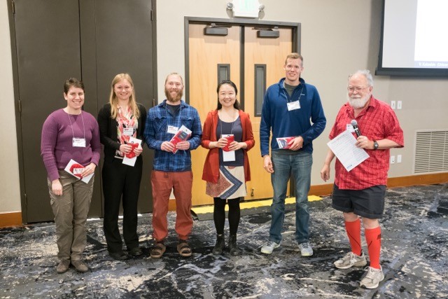 Recipients of the Red Sock Award at the 2017 SIAM Conference on Applications of Dynamical Systems. From left: Genevieve Jay Brett (Massachusetts Institute of Technology), Stephanie Dodson (Brown University), Ian McGahan (Utah State University), Vicky Chuqiao Yang (Northwestern University), and Isaac Yeaton (Virginia Tech), and James Yorke (presenter, University of Maryland, College Park). Image credit: Ernie Barreto.