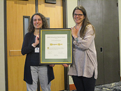 Margaret Beck (right) received the J. D. Crawford Prize from Evelyn Sander, Crawford Prize Committee Chair, at the SIAM Conference on Applications of Dynamical Systems.