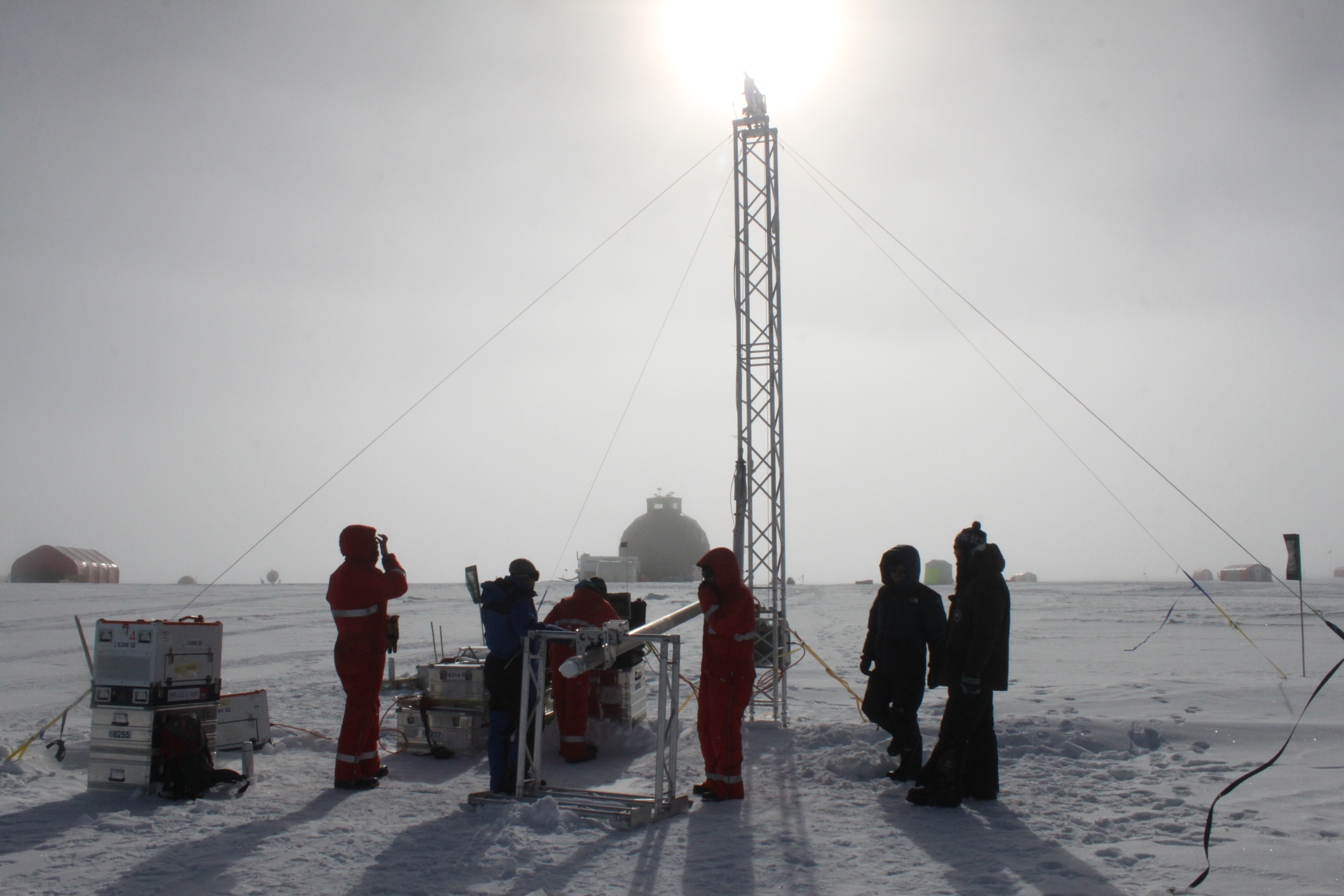 Climate researchers on the site of the Eastern Greenland Ice-core Project use a drill to collect ice core samples. Public domain image.