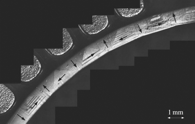 <strong>Figure 2.</strong> Bending by phase transformation of the tetragonal phase of a single crystal from a NiMnGa alloy. The arrows depict the direction of magnetization. Figure courtesy of [5].