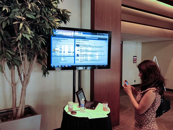 Karthika Muthukumaraswamy with the screen showing live tweets at #SIAMAN12.