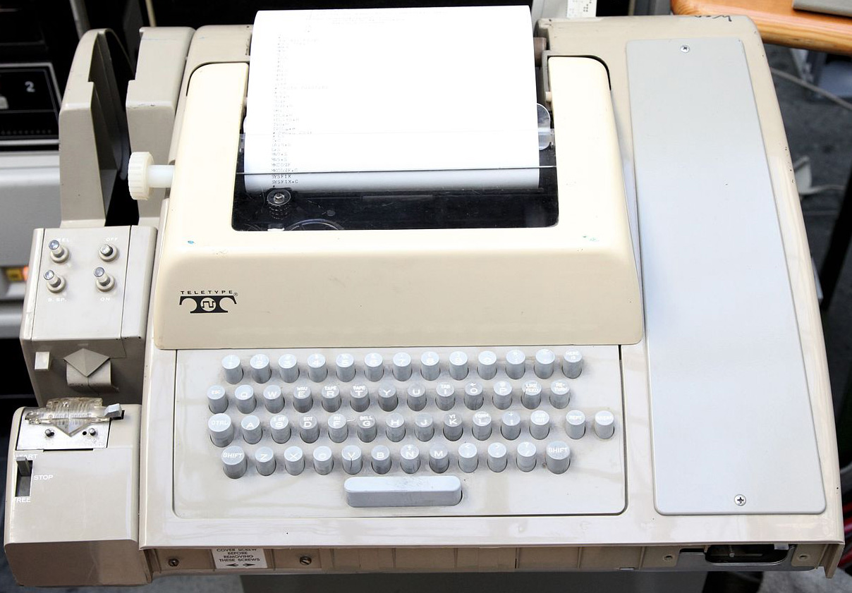 <strong>Figure 1.</strong> John Nash used a similar teletype to access the Data General NOVA and ECLIPSE. Note the paper tape reader and punch. The noise was such that he requested (and received) ear protectors. This image is under a <a href="https://commons.wikimedia.org/wiki/File:Teletype.jpg" rel="noopener noreferrer" target="_blank">Creative Commons license</a>.