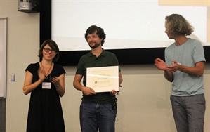 SIAG/AG Chair Agnes Szanto (left) and Vice-Chair Jan Draisma (right) present the SIAG/AG Early Career Prize to Pierre Lairez of Inria Saclay Ile-de-France.
