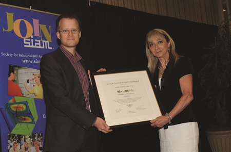 Joscha Gedicke of Humboldt University of Berlin accepted a 2013 SIAM Student Paper Prize from Irene Fonseca. The two other recipients were Keiichi Morikuni of the Graduate University of Advanced Studies (Sokendai), Japan, and Vladislav Voroninski of the University of California, Berkeley; all three gave talks based on their papers in a mini-symposium at the SIAM Annual Meeting.